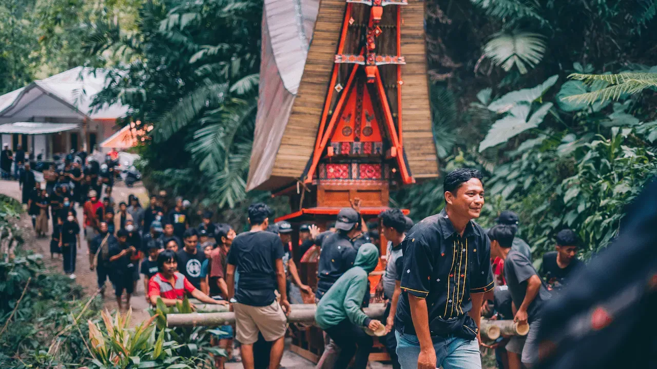 Traditional funeral procession with ornate casket carried through a tropical forest