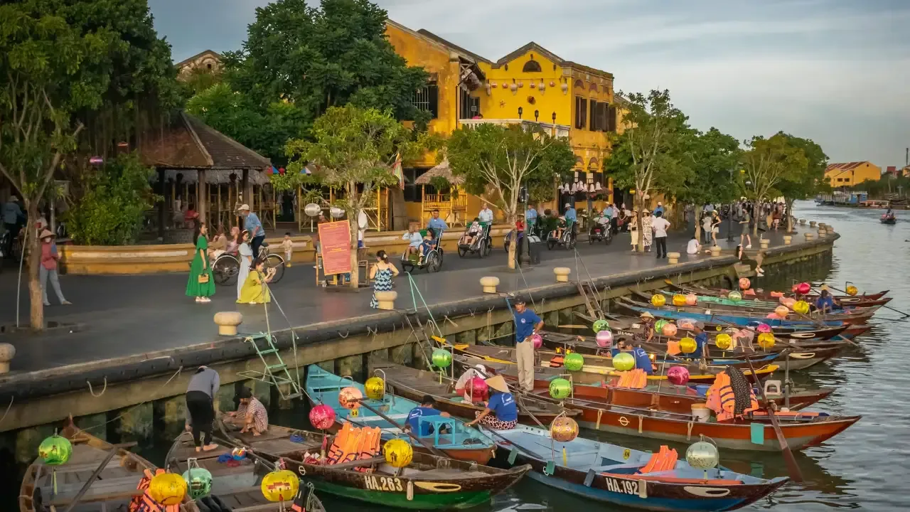 Tourists walking along the canals in Hoi An with long boats