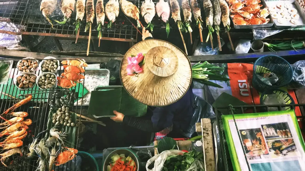 Woman grilling fish on boat Bangkok